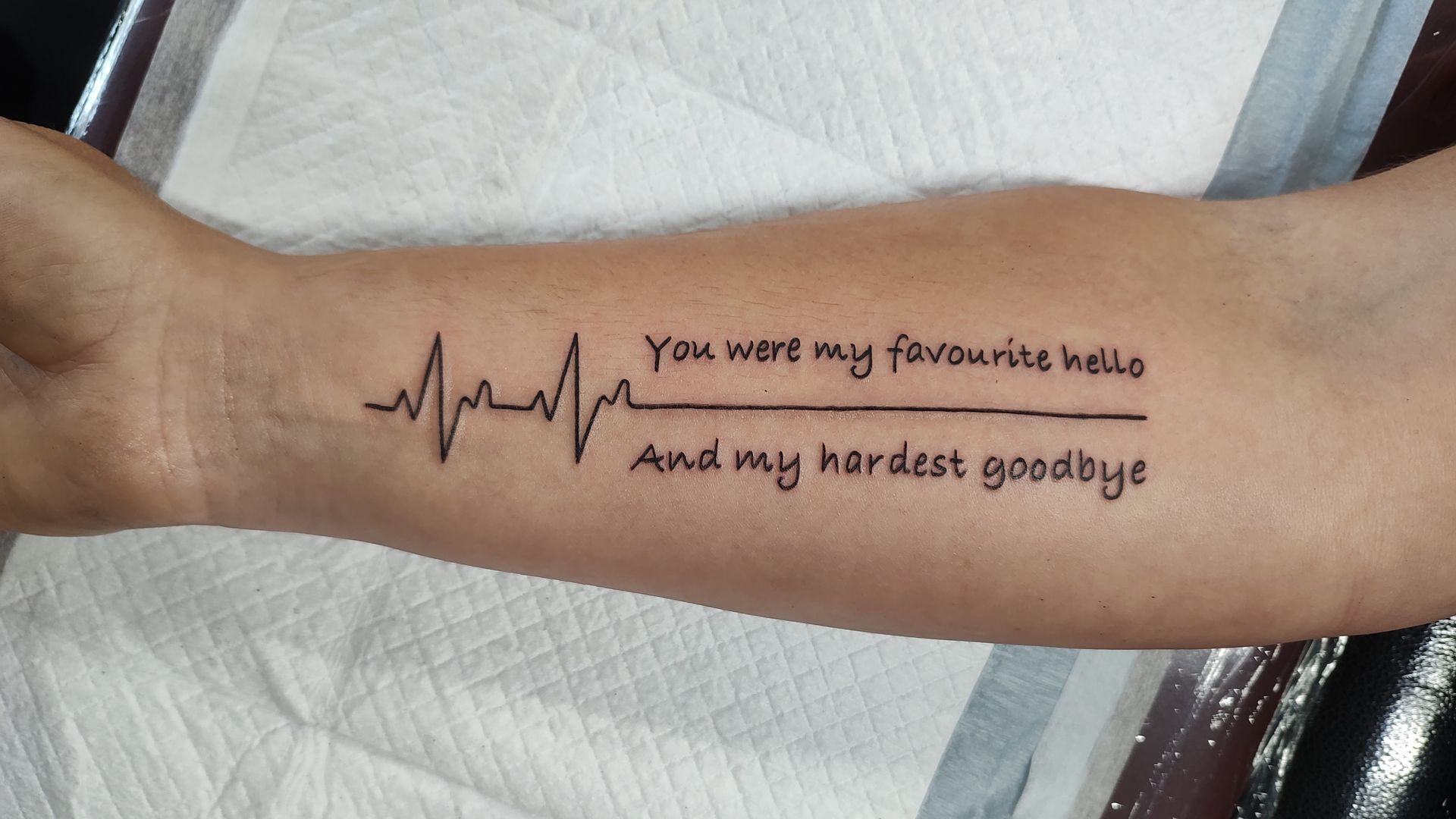 A person has a tattoo on their arm that says you were my favourite home and my hardest goodbye