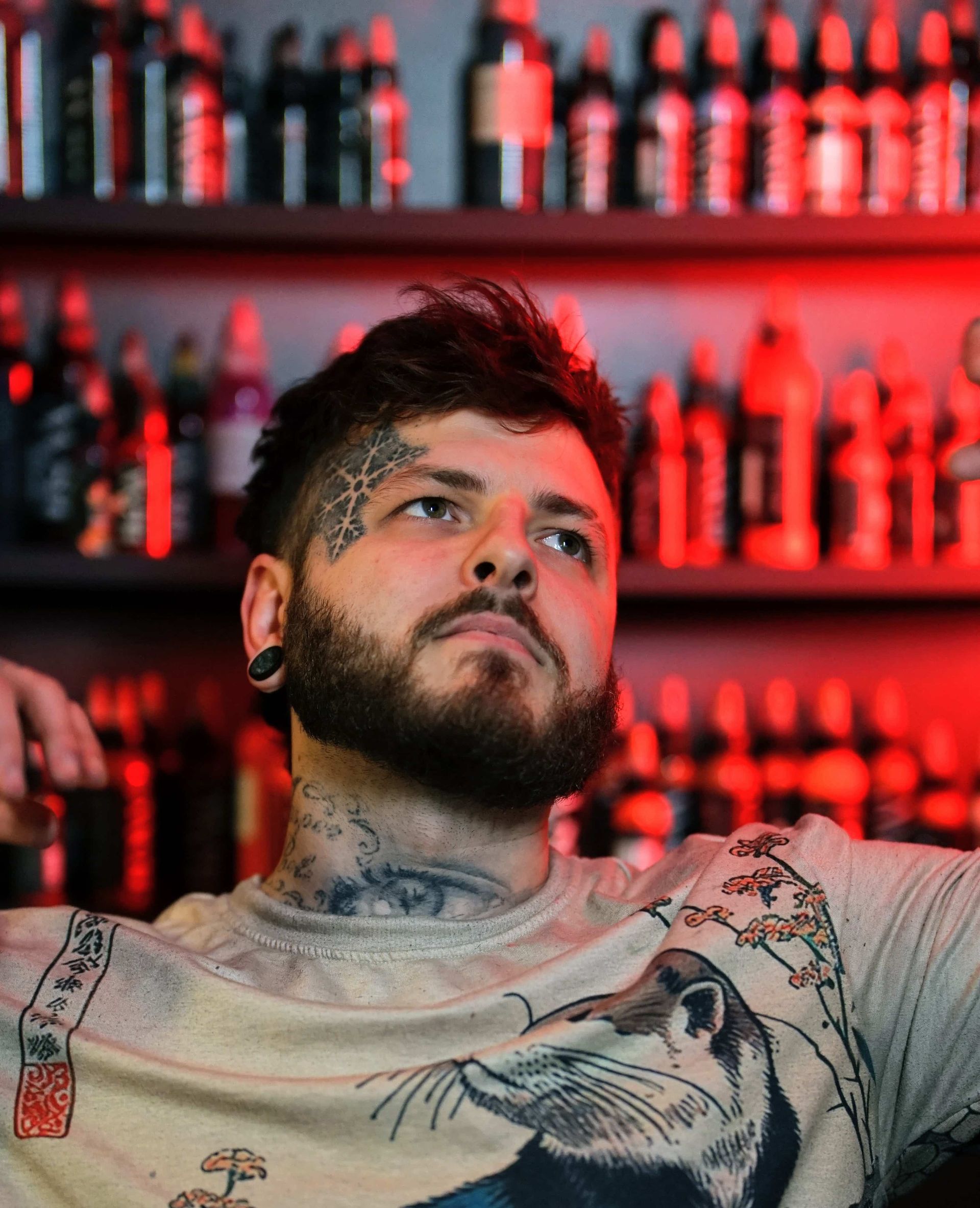 A man with long hair and a beard is standing in front of a red light.