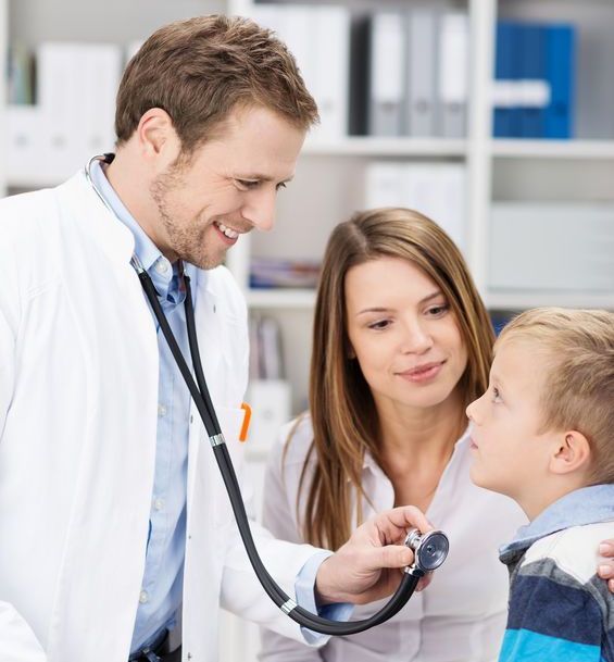 doctor using stethoscope on young boy patient in clinic 