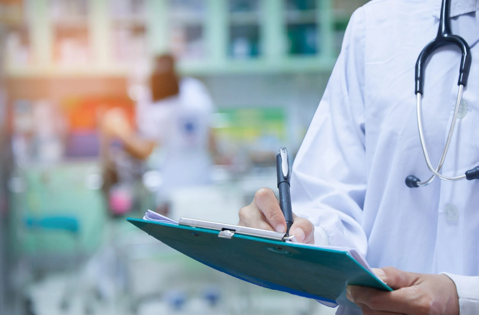 Doctor in white coat writing on clipboard, stethoscope around neck, hospital setting.