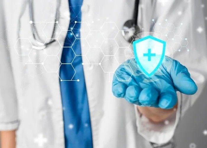 Doctor in lab coat and glove holding a glowing shield with a cross symbol, healthcare concept.