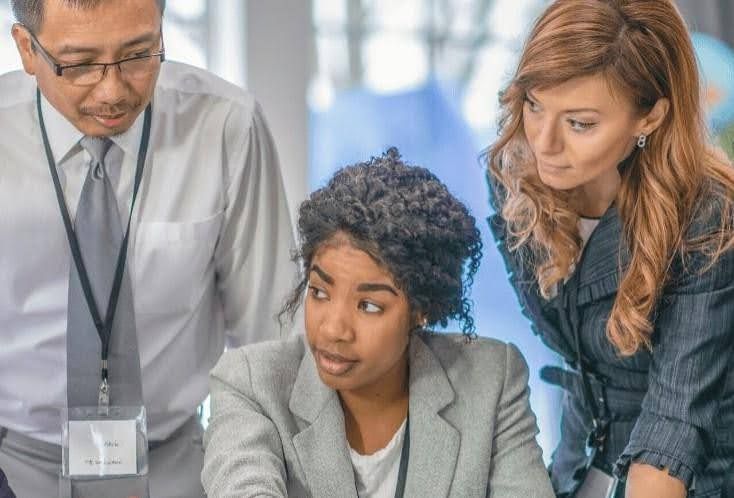 Three coworkers looking at something together.