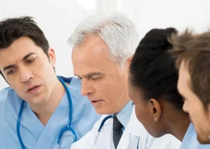Medical professionals in scrubs and lab coats review documents together.