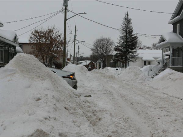 Snow-covered residential street with high snowbanks.