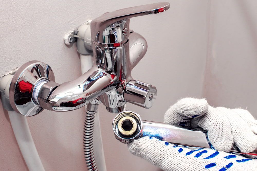 Person is Fixing a Bathroom Faucet With a Wrench — Off-Tap Plumbing NQ In Currajong, QLD