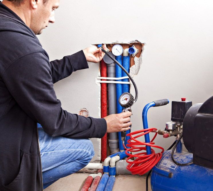Man is Working on a Pipe With an Air Compressor — Off-Tap Plumbing NQ In Currajong, QLD