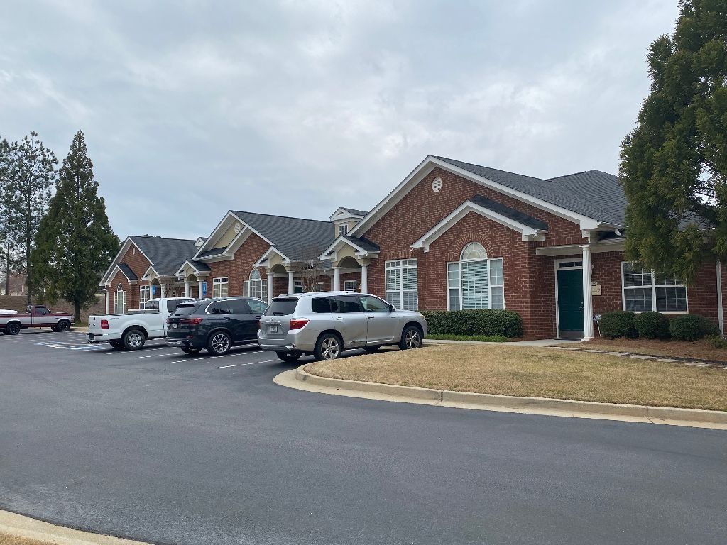 A row of houses with cars parked in front of them.