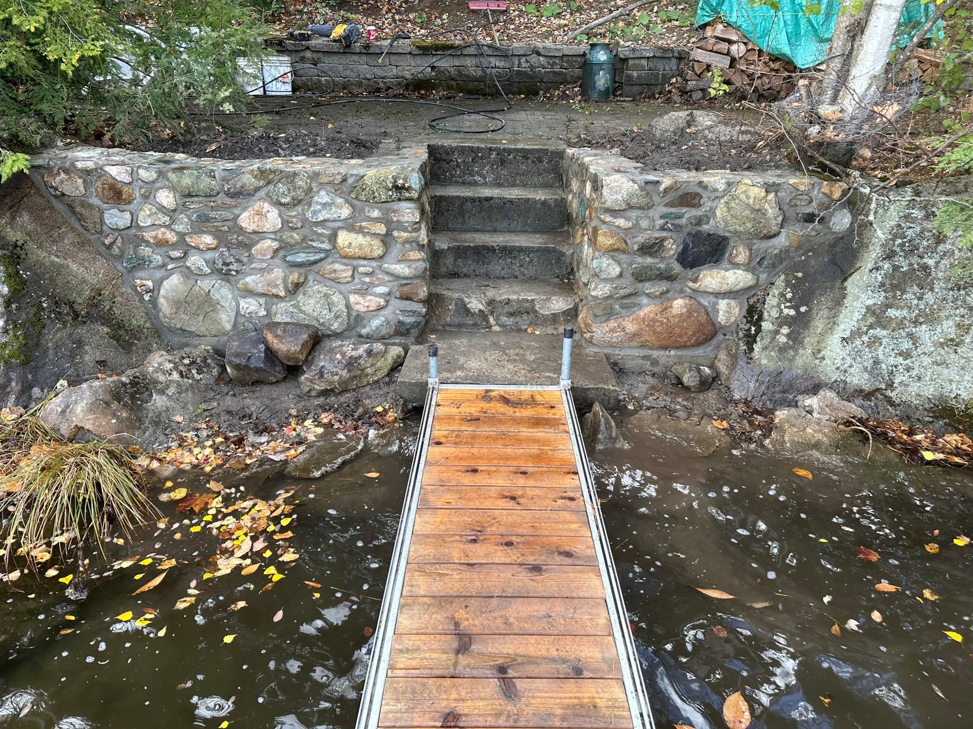 Des marches en pierre mènent d'un quai à une zone herbeuse où l'on aperçoit l'eau et la végétation.