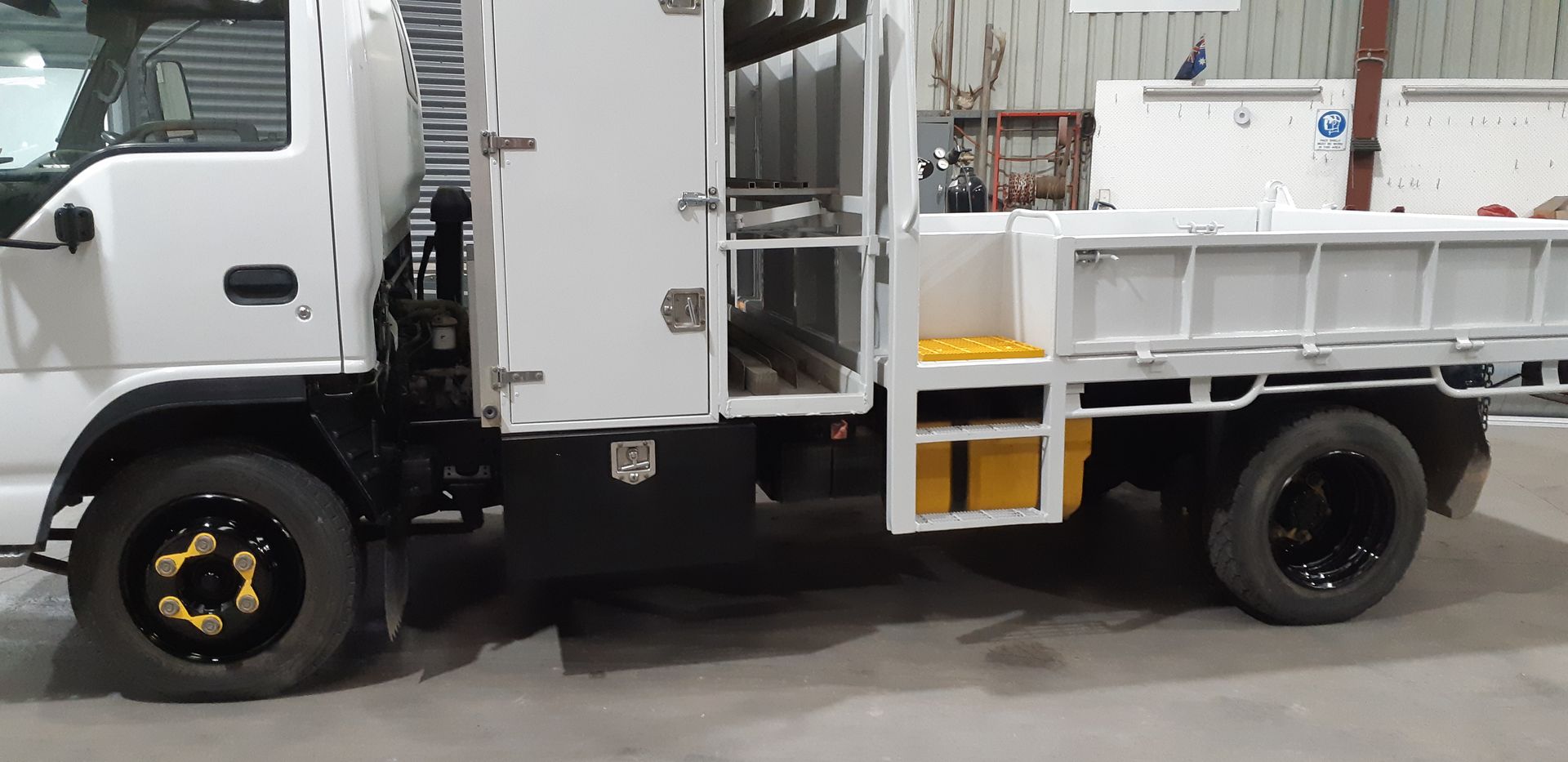 A white truck with black wheels is parked in a garage.