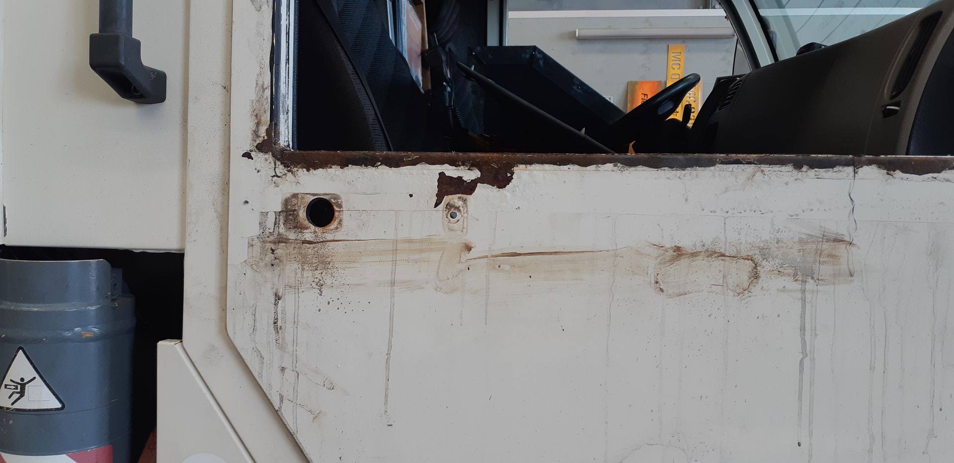 A close up of a white truck door with a hole in it.