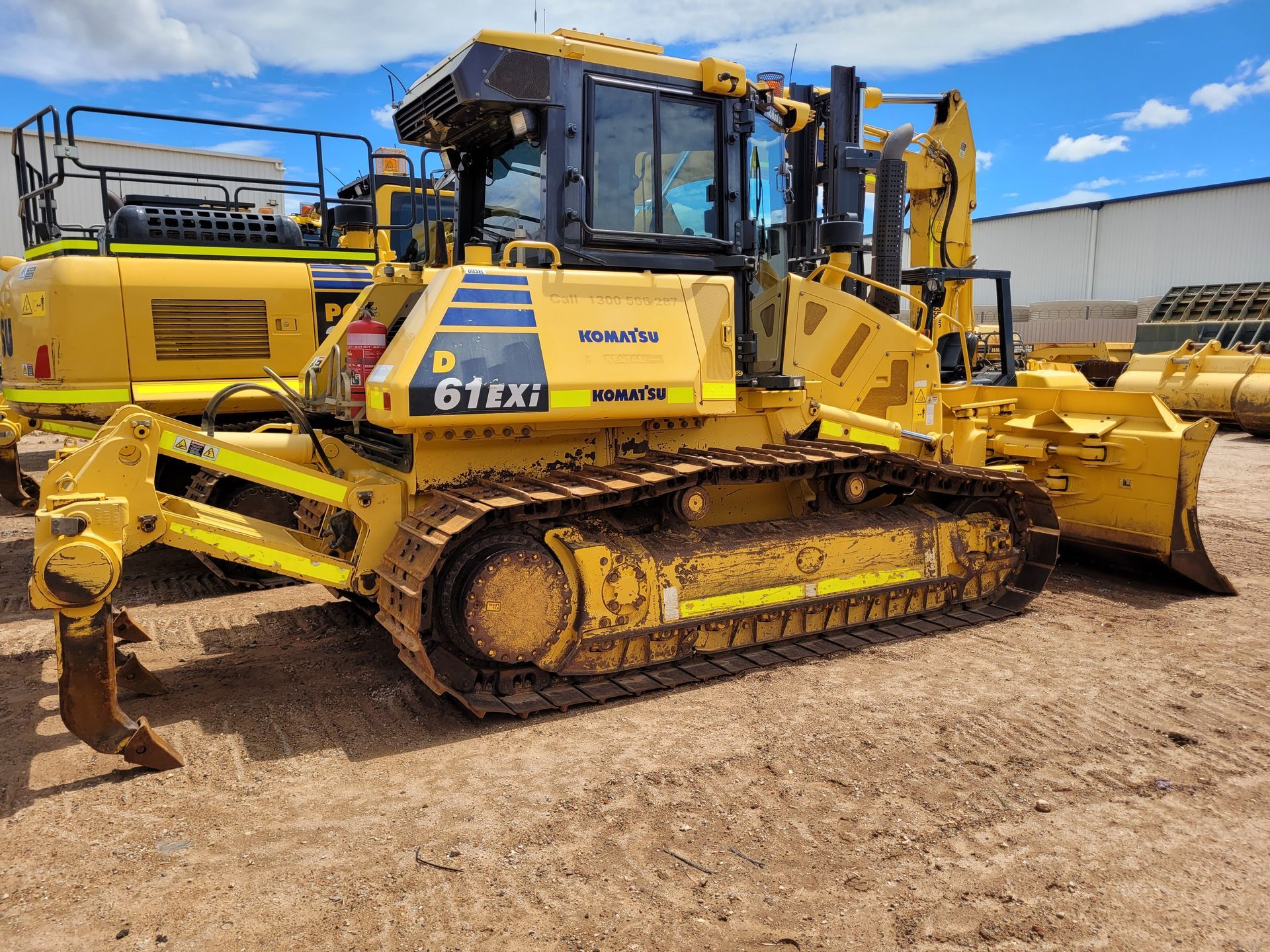 A yellow bulldozer is parked in a dirt lot.
