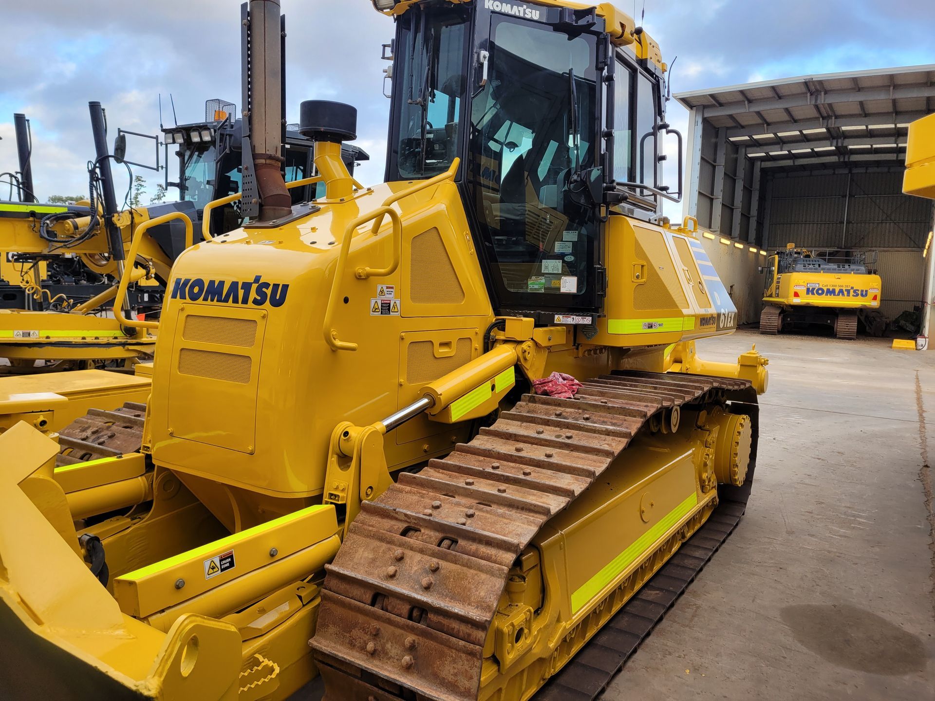 A yellow komatsu bulldozer is parked in a parking lot