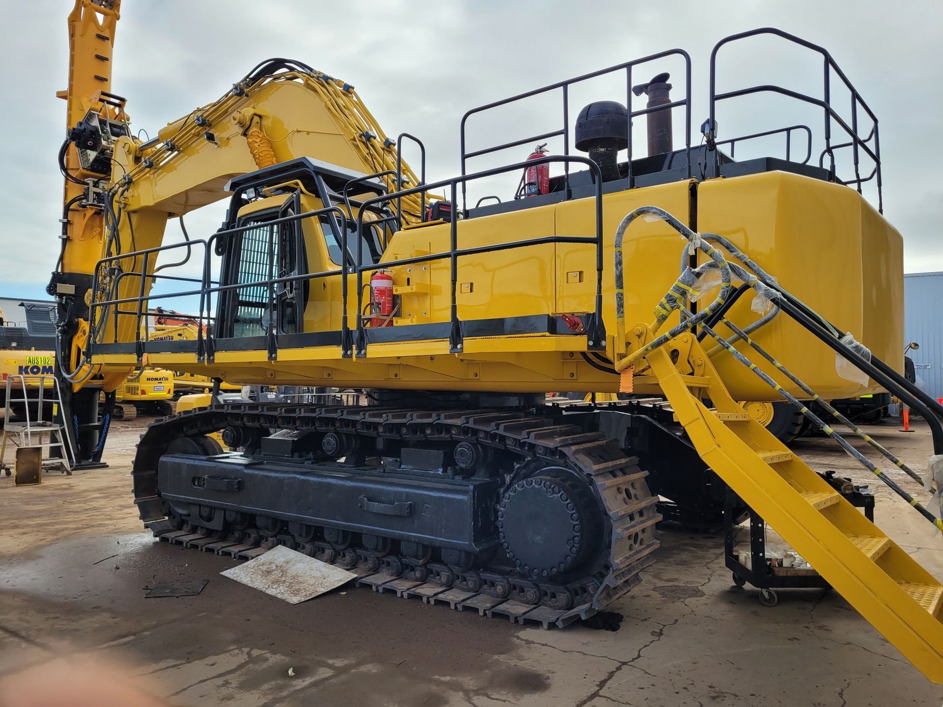 A large yellow excavator is parked in a parking lot.