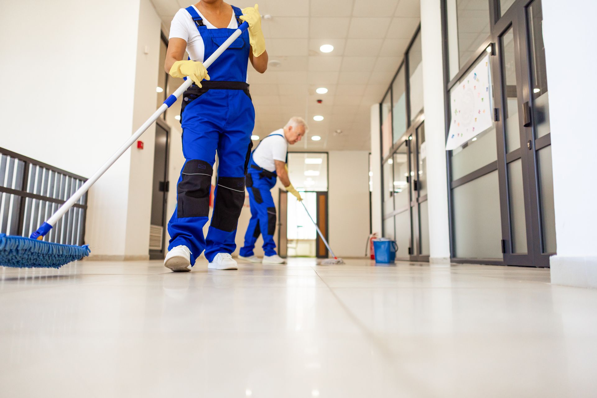 A man and a woman are cleaning the floor of a building.