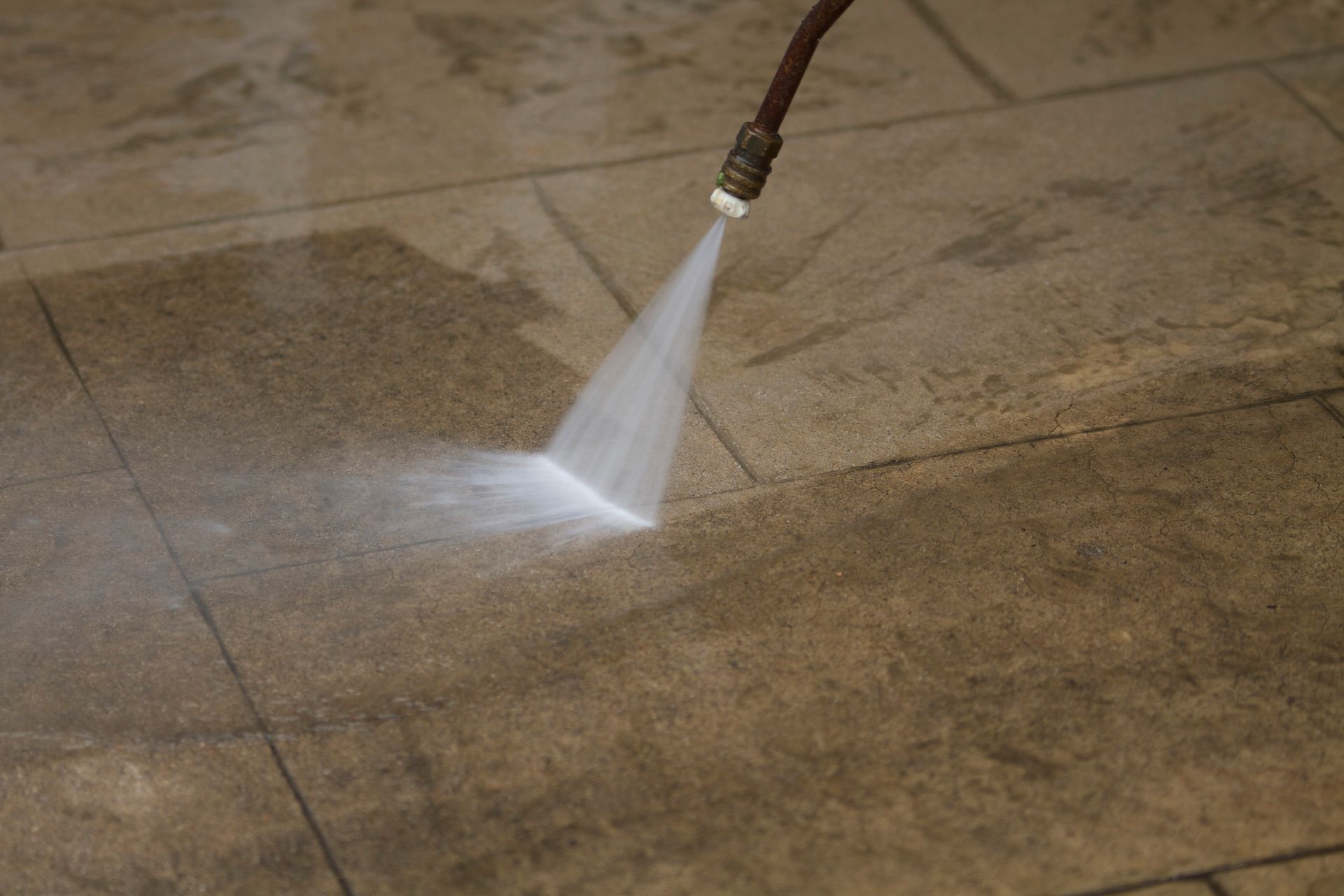 Power washer cleans a tiled floor with a stream of water. Power washer cleans a tiled floor with a stream of water.