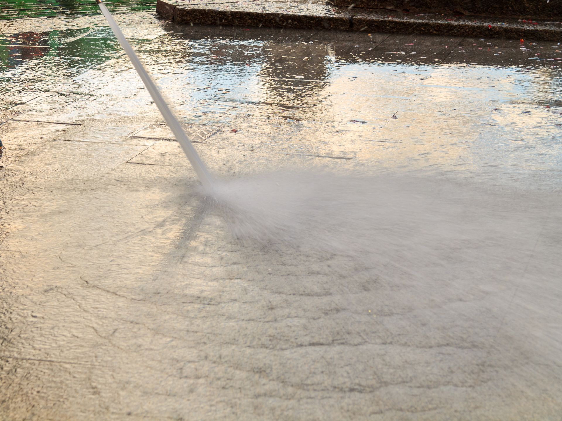 Water from a pressure washer hits a concrete curb. Water from a pressure washer hits a concrete curb.