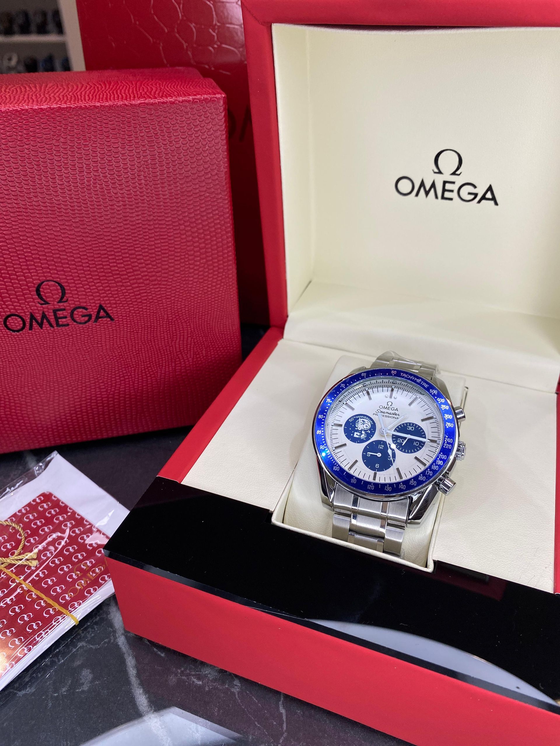 Un reloj Omega está en una caja roja sobre una mesa.