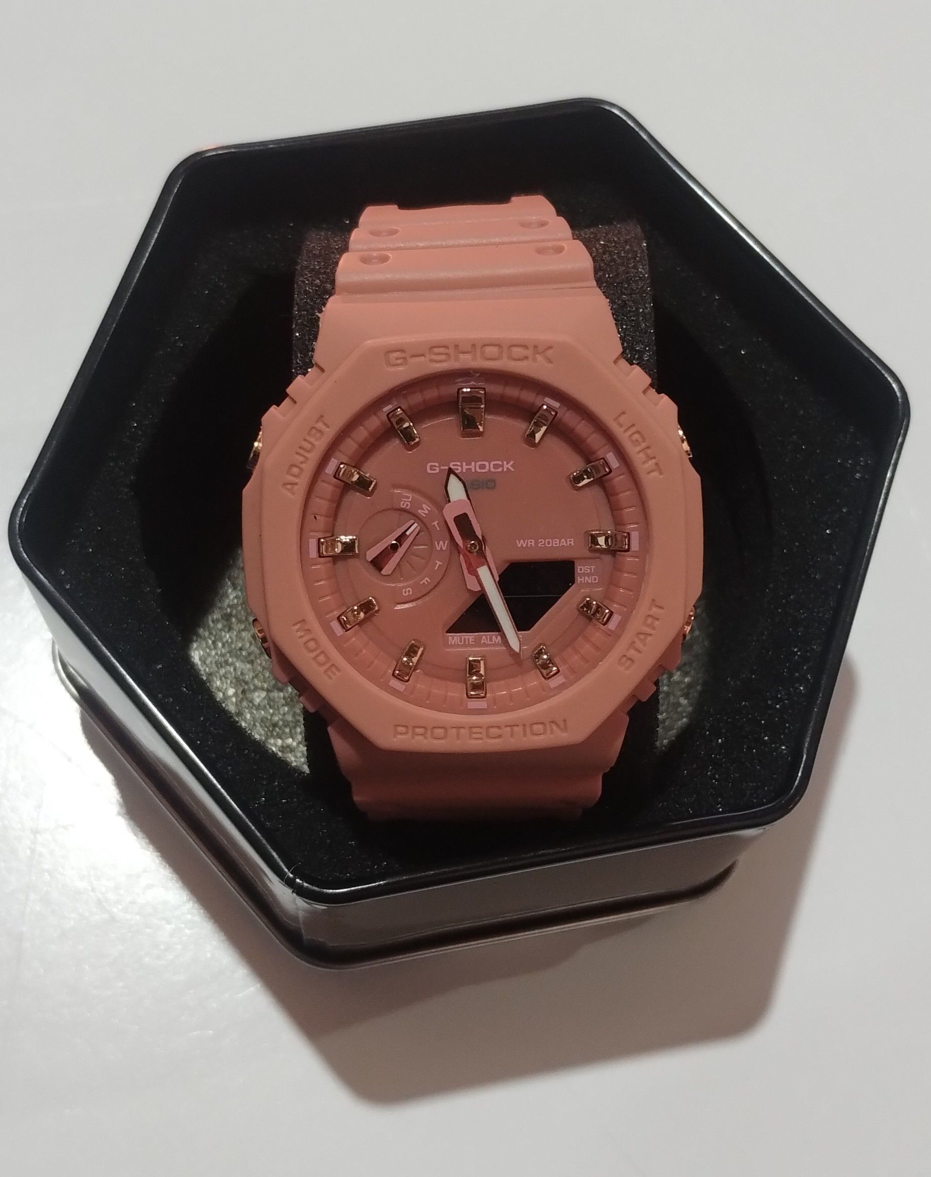 Un reloj G-Shock rosa se encuentra en una caja negra.