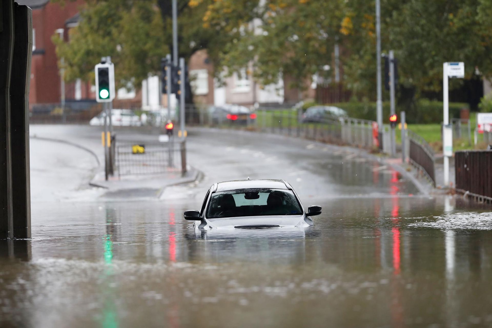 A car is driving through a flooded street.