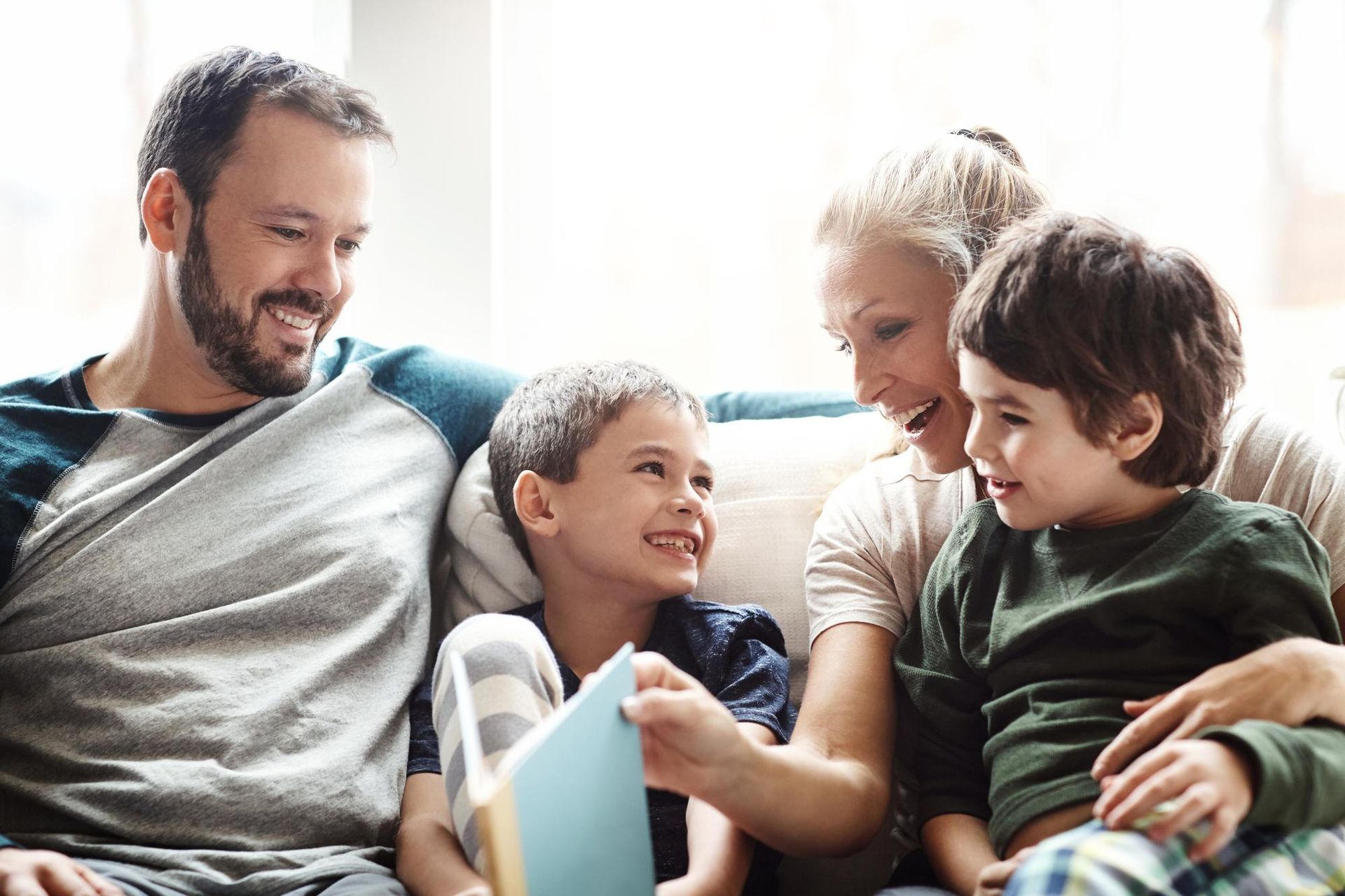 A family is sitting on a couch reading a book together.