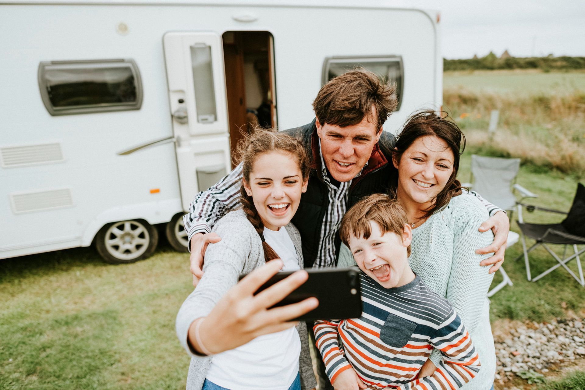 A family is taking a selfie in front of a trailer.