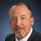 A man in a suit and tie is smiling for the camera.