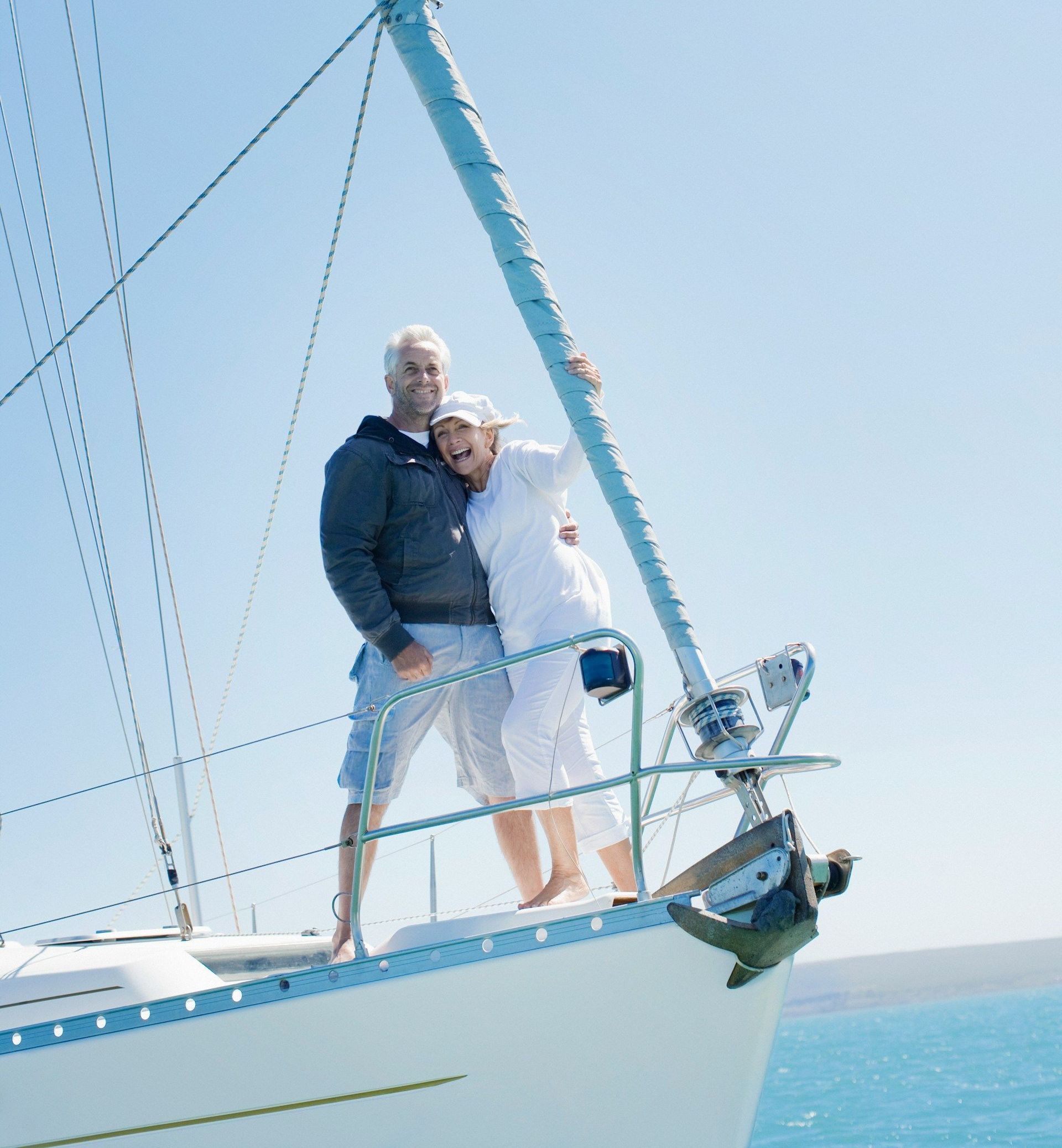 A man and woman are standing on the side of a sailboat