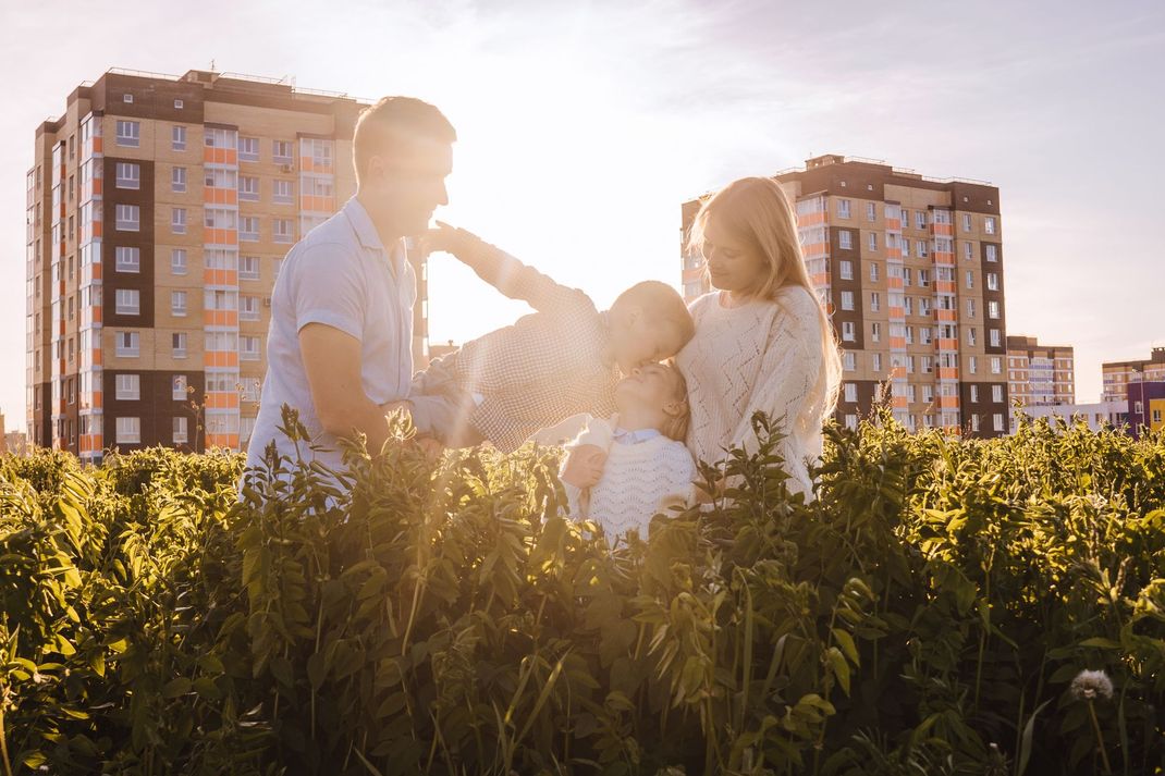A family is standing in a field with buildings in the background.