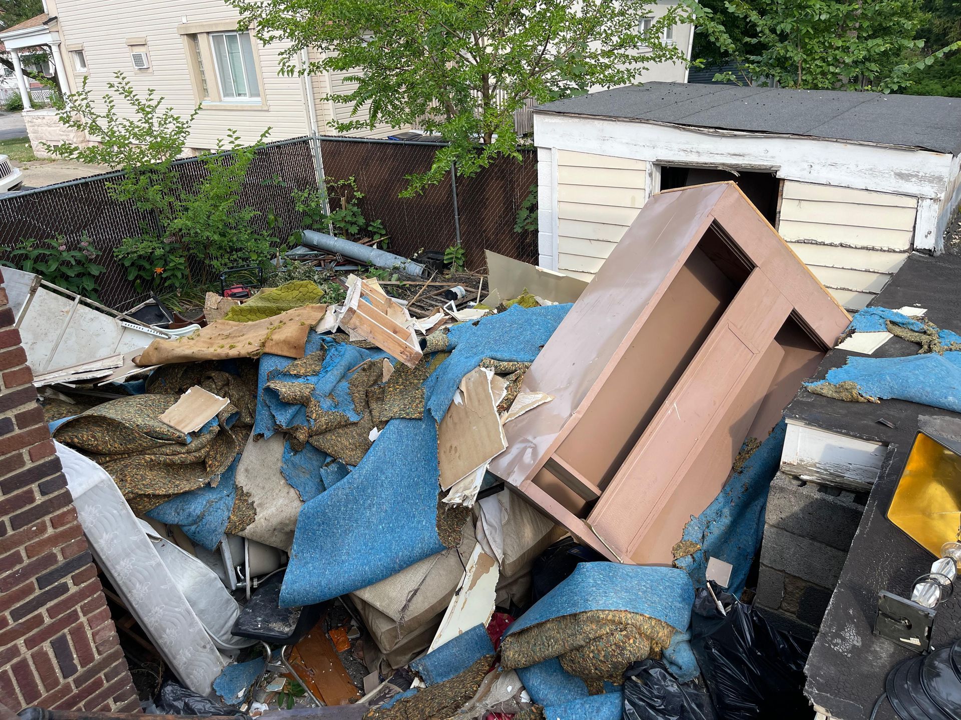 A pile of junk is sitting on the ground in front of a garage.