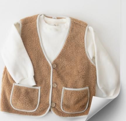 Un chaleco marrón y una camisa blanca están en un trozo de papel.