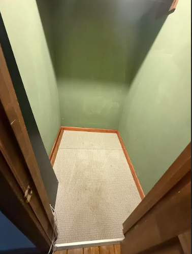 Narrow hallway with green walls, light carpet, and wooden door frames.