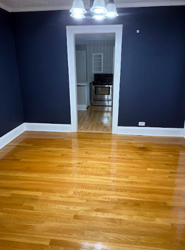 Hardwood floor room with navy blue walls, white trim, and doorway to kitchen.