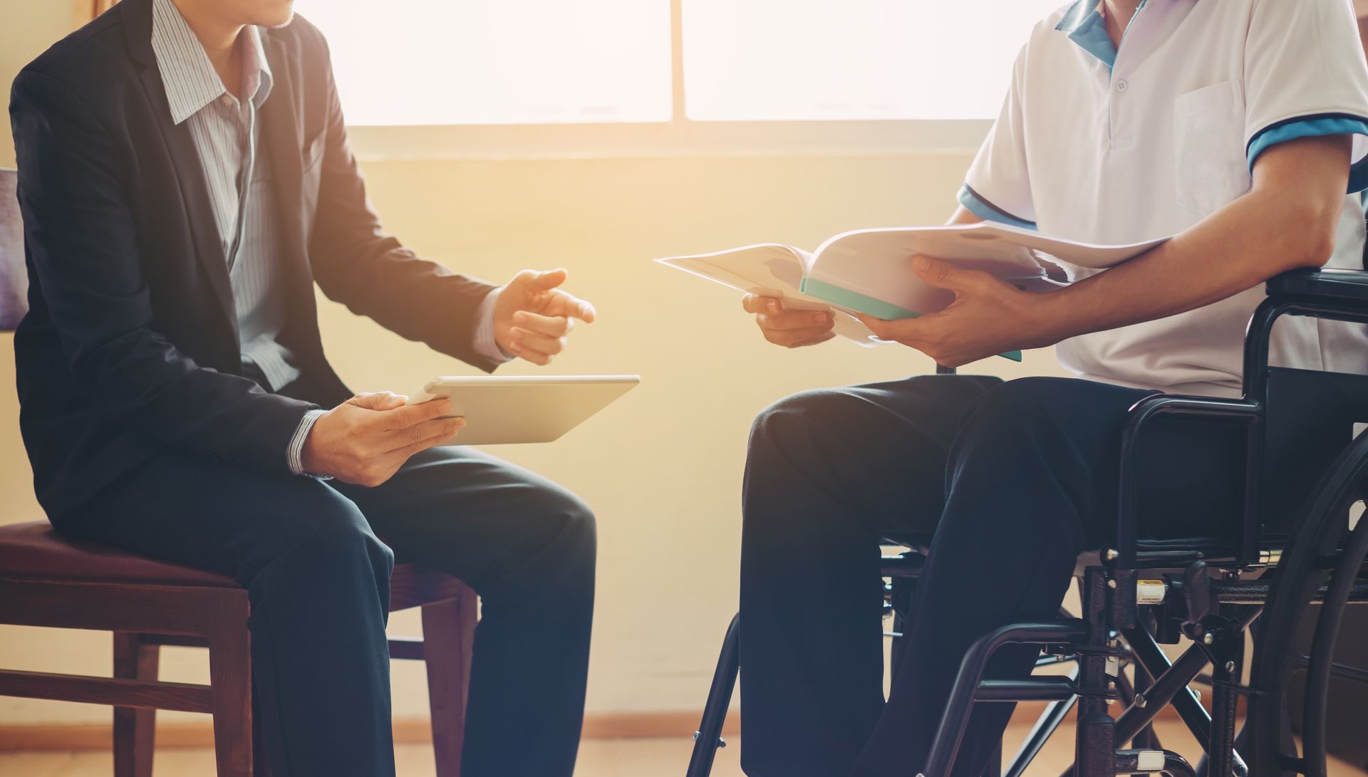 A man in a suit is talking to a man in a wheelchair.