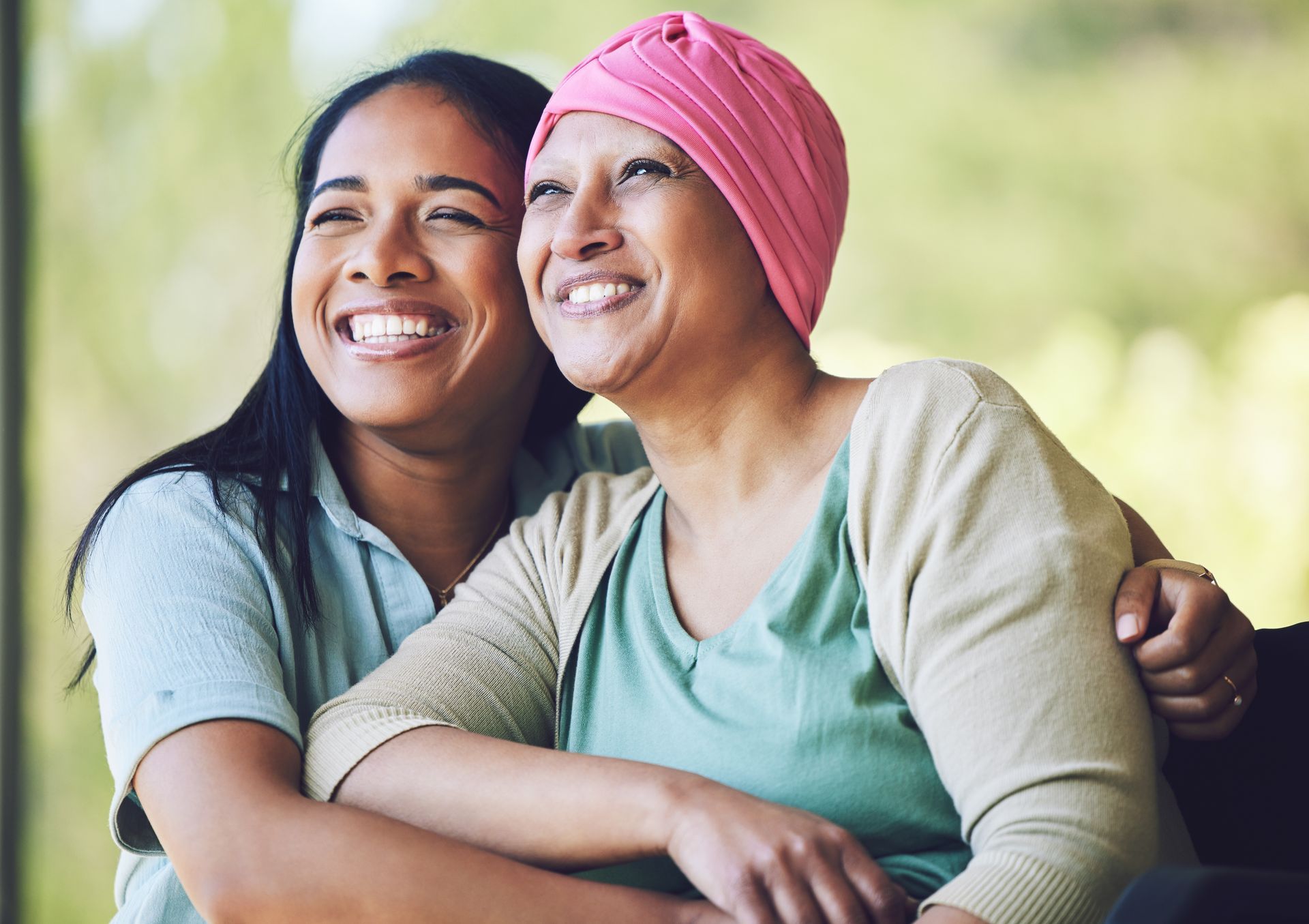 A woman with cancer is hugging her daughter who is wearing a pink turban.