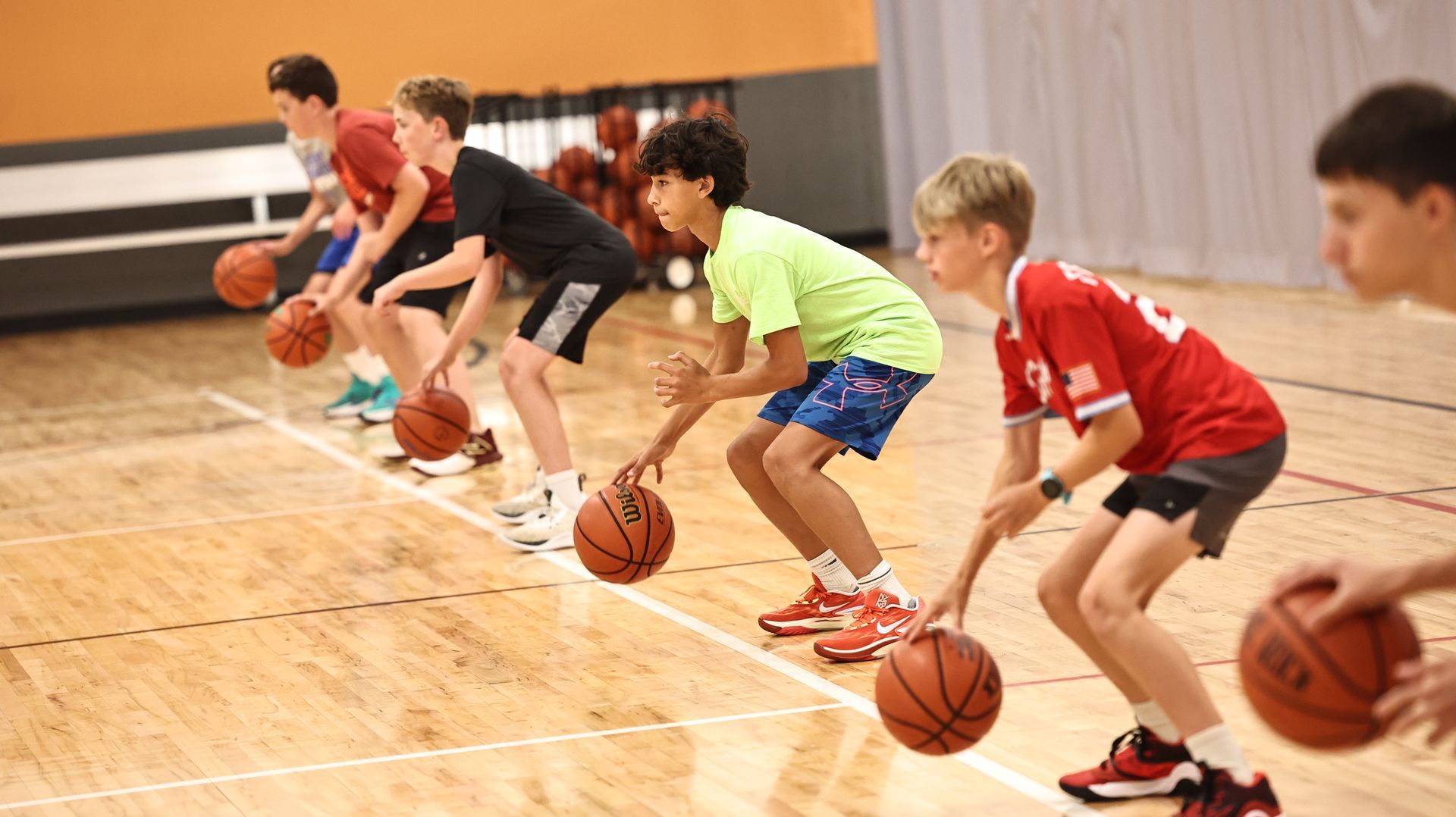 Two young boys are playing basketball on a court.