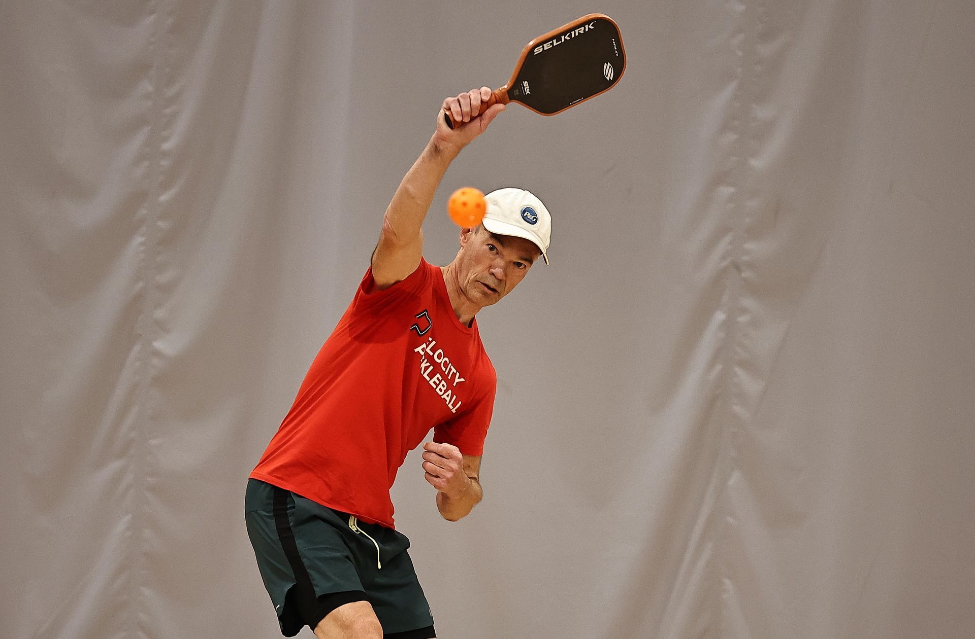 A man playing tennis with a wilson bag in the background