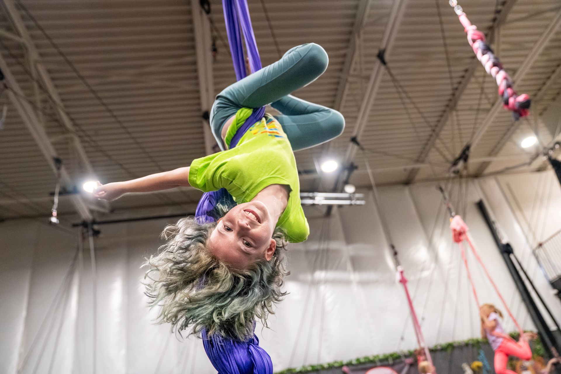 A young girl is doing aerial acrobatics in a gym.