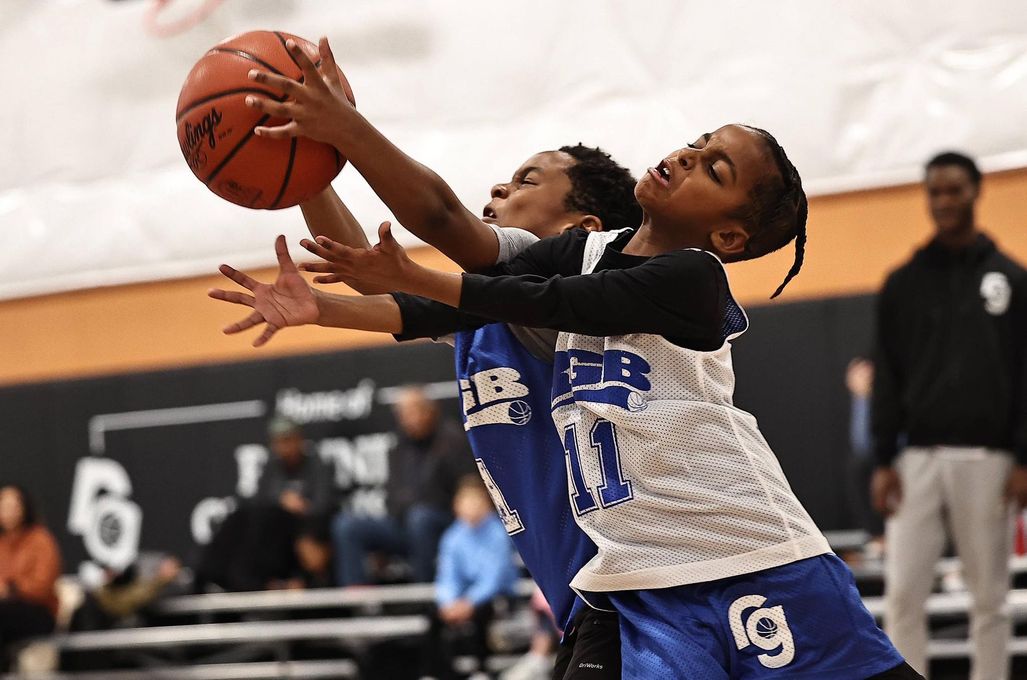 Two young boys are playing basketball on a court.