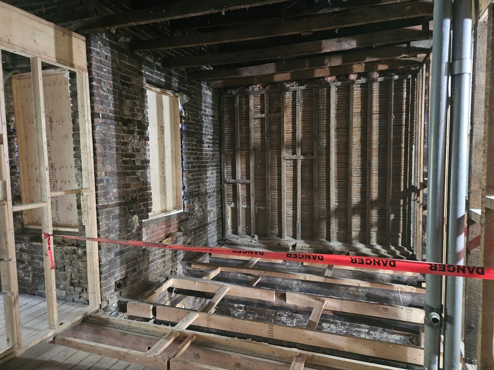 Une pièce avec un mur en briques et un plancher en bois en construction.