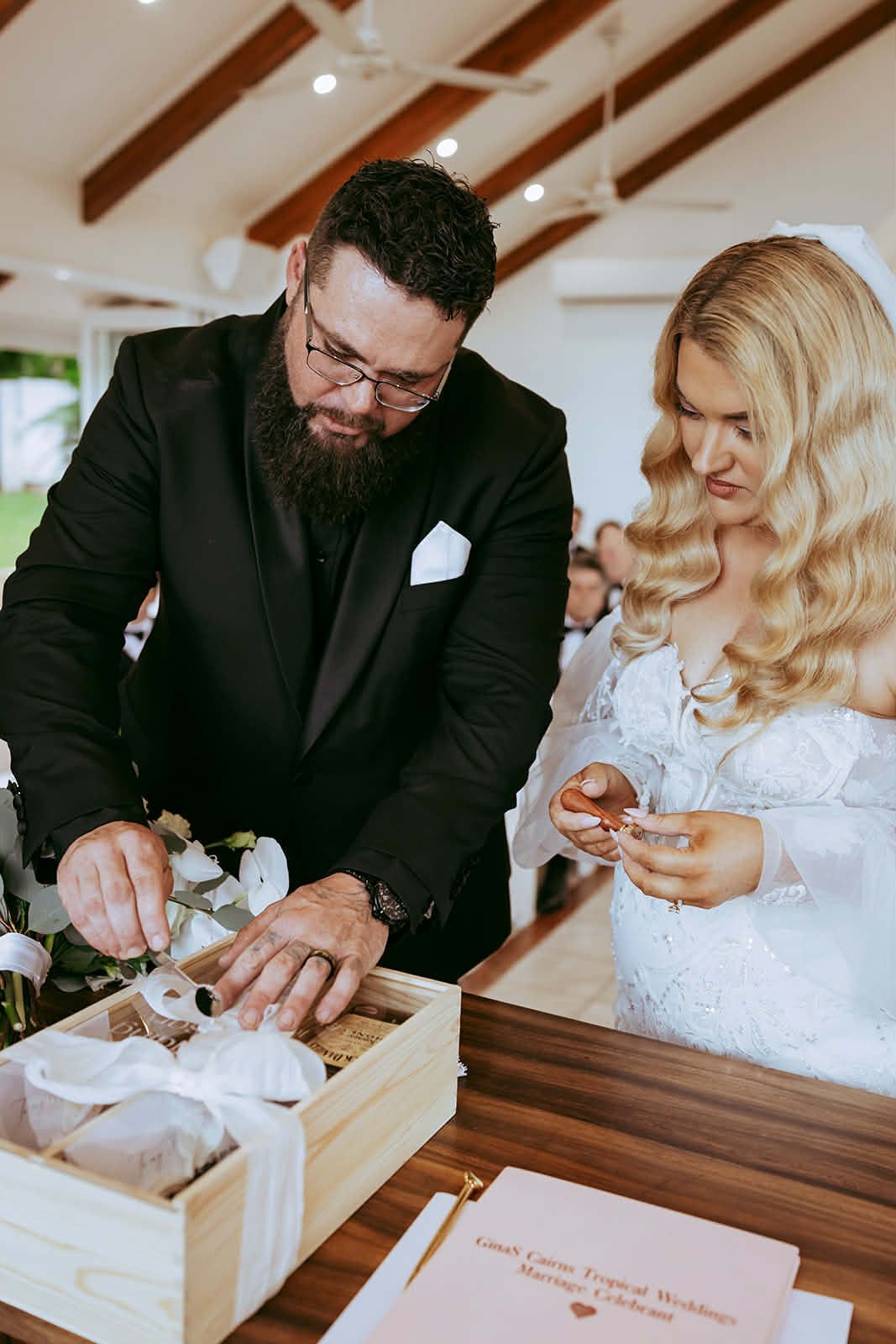 Two people signing a document at a wooden table during a wedding ceremony