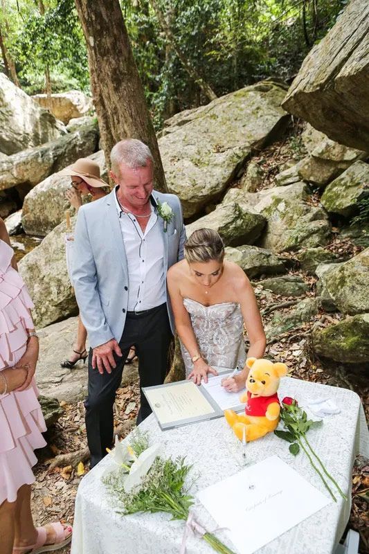 A Bride and Groom Are Signing a Wedding Certificate Beside the River — GinaS Cairns Tropical Weddings in Parramatta Park, QLD