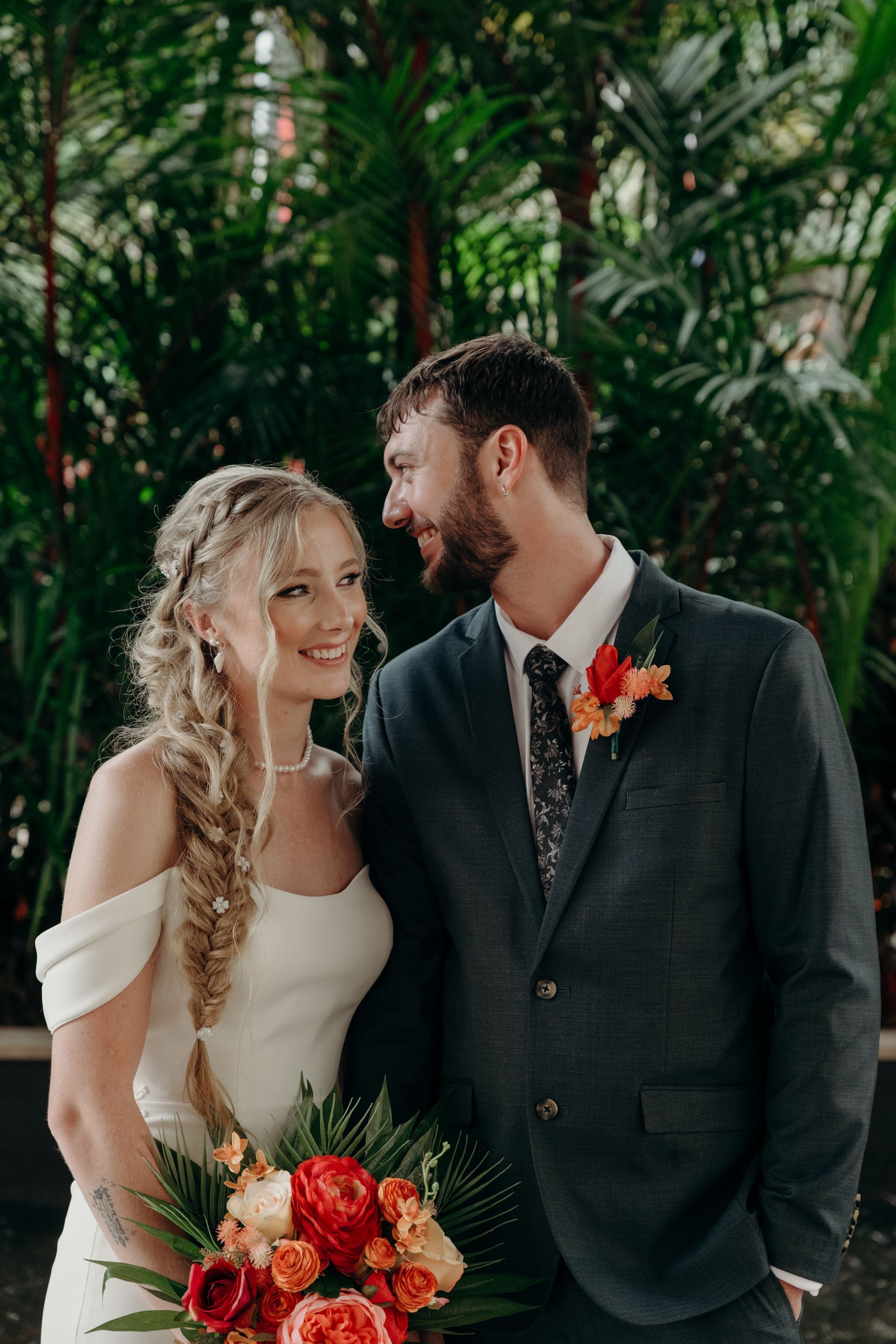 Bride and groom gazing at each other. Bride holds bouquet. Tropical foliage backdrop - GinaS Cairns Tropical Weddings in Parramatta Park, QLD