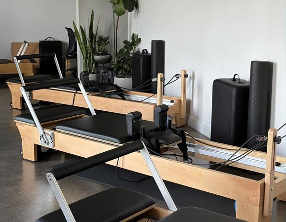 Two pilates machines are sitting in a room next to each other.