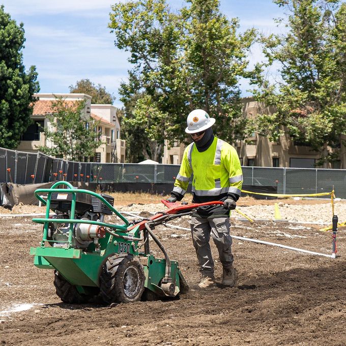 Construction worker operating a tiller on a construction site.
