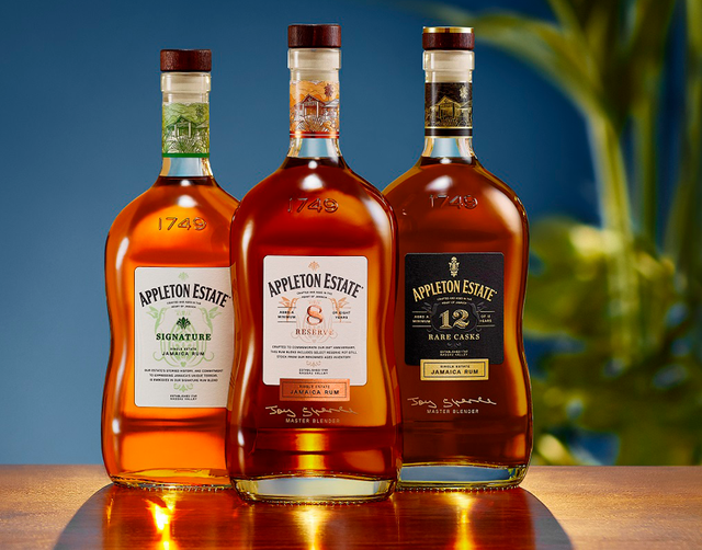Three bottles of whiskey are lined up on a wooden table