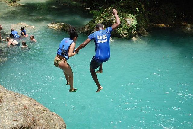 A man in a red shirt is jumping into the water