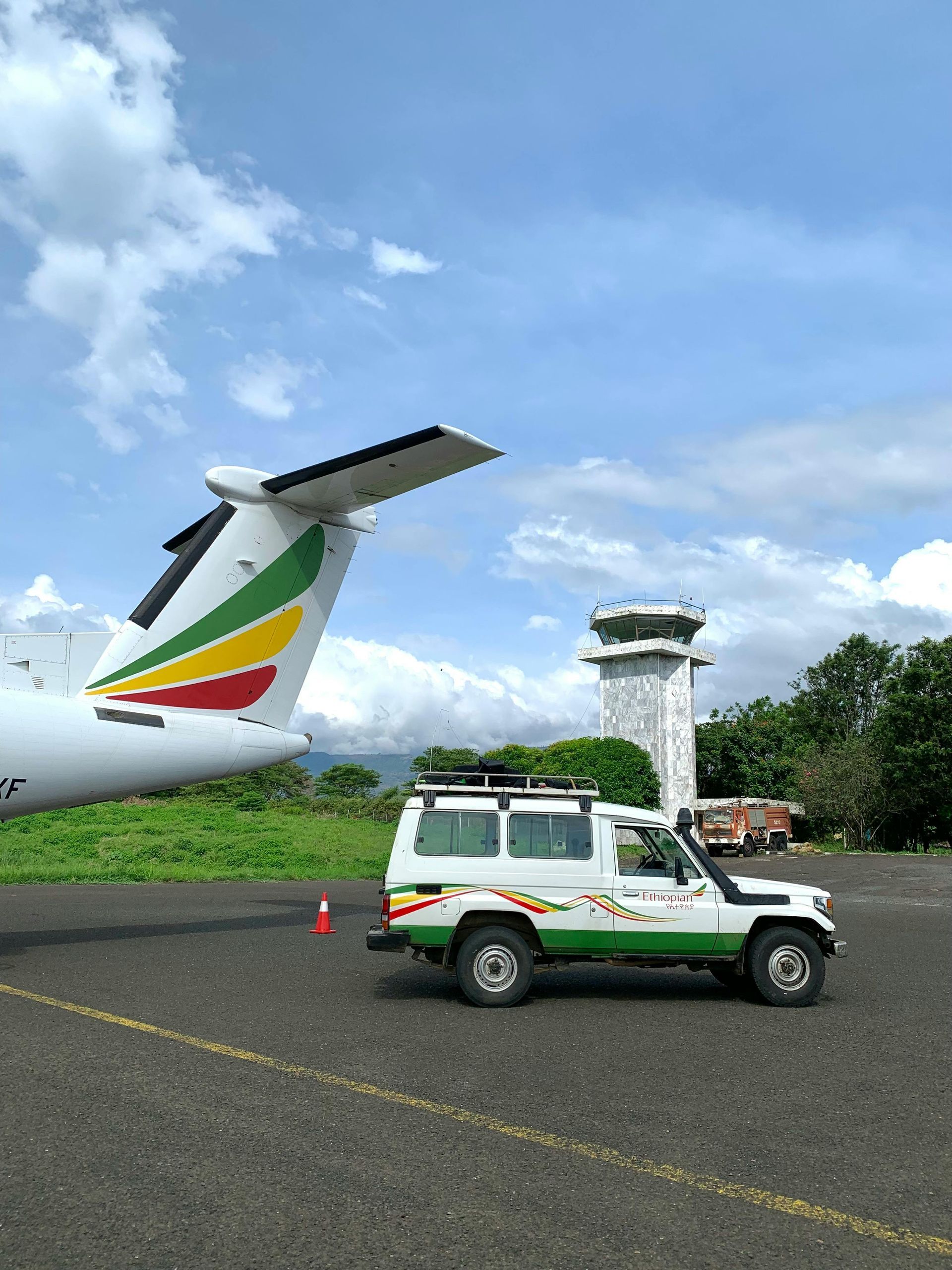 A car is parked next to an airplane on a runway.