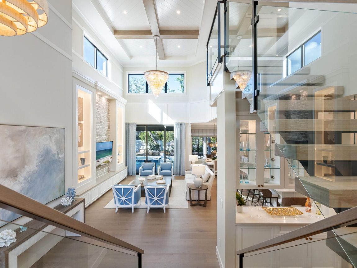 A kitchen with white cabinets , stainless steel appliances , hardwood floors and a large island.