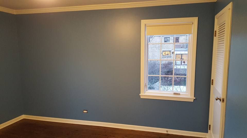 An empty room with blue walls and a window.