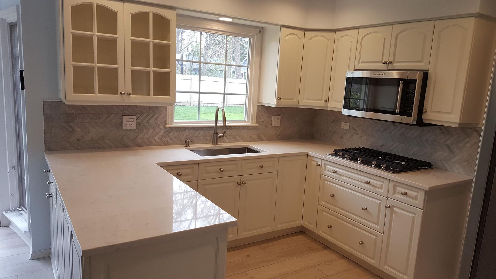 A kitchen with white cabinets and a stove top oven.